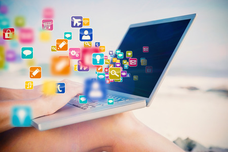 Woman sitting on beach using her laptop with colourful computer applications