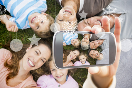 Hand holding smartphone showing extended family lying in circle at park