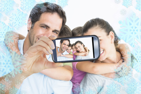 Hand holding smartphone showing smiling young family looking at camera together