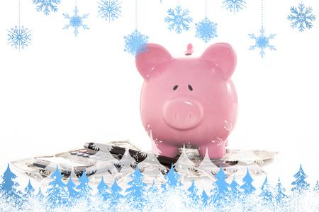 Snowflakes and fir trees against pink piggy bank beside calculator and fountain penの写真素材