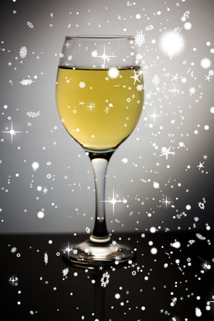 Snow falling against wine glass full of white wineの写真素材