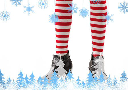 Lower half of girl wearing stripey socks and boots against snowflakes and fir treesの写真素材