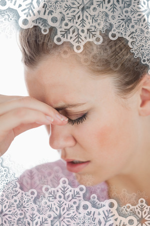 Young woman suffering from headache against snowflakes on silverの写真素材