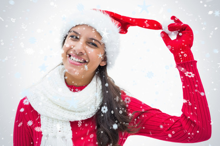 Beautiful festive woman smiling at camera against snow fallingの写真素材
