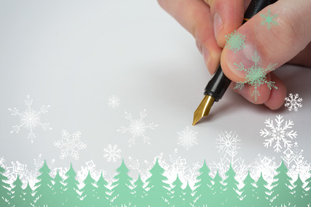Hand writing with fountain pen against snowflakes and fir trees in greenの写真素材
