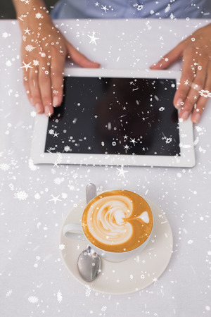 Close-up of digital tablet and coffee on table against snow fallingの写真素材