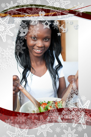 Smiling woman preparing a salad  against christmas frameの写真素材
