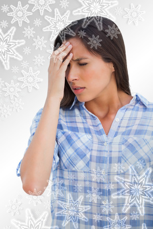 Woman with a headache and hand on forehead against snowflakes on silverの写真素材