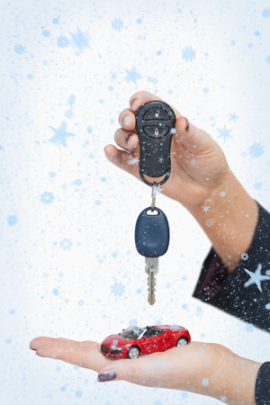 Composite image of Woman holding key and small car with snow fallingの写真素材