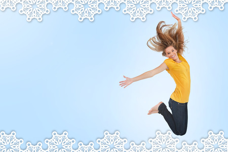 Pretty young woman jumping for joy against snowflake frameの写真素材