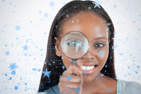 Composite image of young woman with magnifier against snow fallingの写真素材