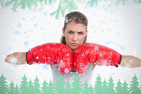 Serious woman with boxing gloves against frost and fir trees in greenの写真素材