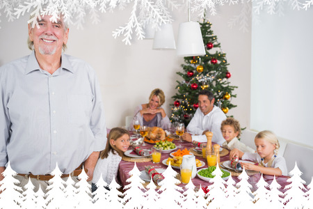 Smiling grandfather standing at the dinner table against fir tree forest and snowflakesの写真素材