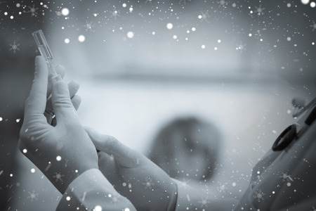 Composite image of doctor preparing a syringe against snowの写真素材