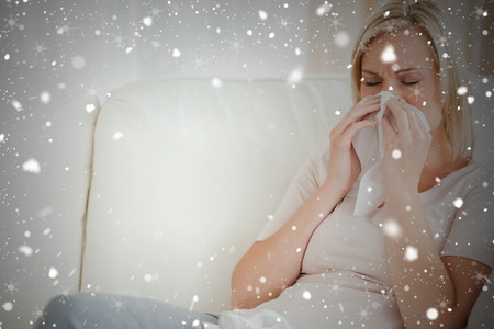 Composite image of woman blowing her nose against snow fallingの写真素材