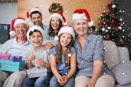 Extended family in Christmas hats with gift boxes in living room against snow fallingの写真素材
