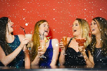 Composite image of Laughing friends holding cocktails against snow fallingの写真素材
