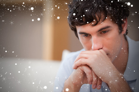 Composite image of thoughtful man in the living room against snowの写真素材