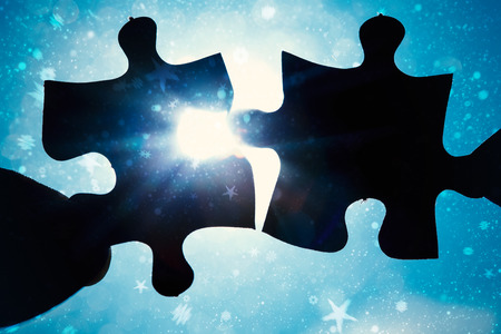 Composite image of hand holding two jigsaw pieces against snowの写真素材
