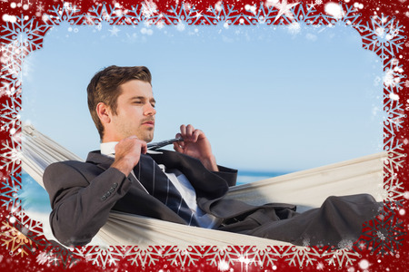 Composite image of snow frame against businessman man lying in hamock taking off his tieの写真素材