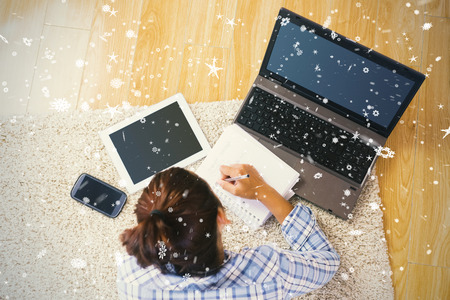 Brunette young student using her tablet and notebook for doing homework against snow fallingの写真素材