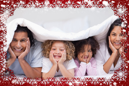 Composite image of family hiding under the blanket against snowの写真素材