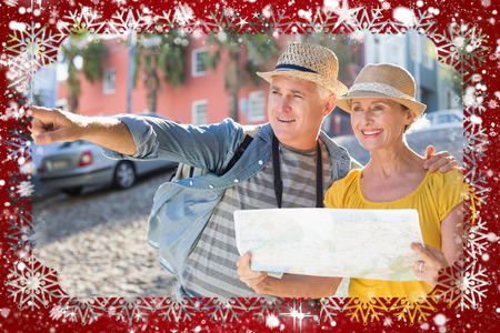 Happy tourist couple using map in the city against snowの写真素材