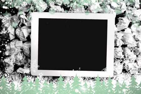 Composite image of tablet screen against snowflakes and fir trees in greenの写真素材