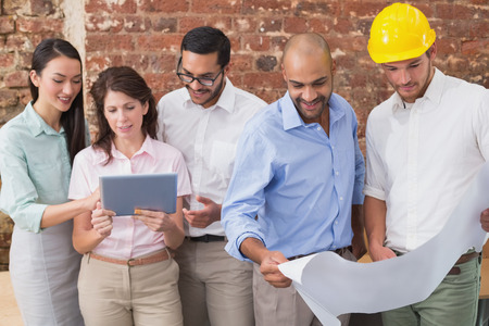 Architect colleagues working on blueprints and digital tablet at office