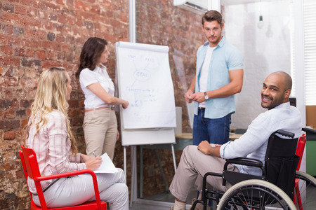 Man in wheelchair smiling at camera during presentation in the office