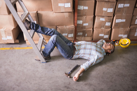 Side view of male worker lying on the floor in warehouseの写真素材