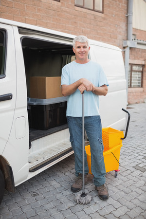 Portrait of janitor standing by vehicle in front of warehouseの写真素材