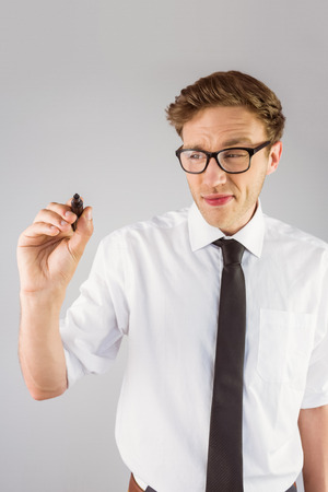 Geeky businessman writing with marker on grey backgroundの写真素材