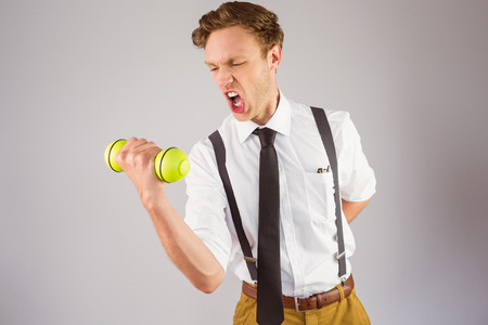 Geeky businessman lifting a dumbbell on grey backgroundの写真素材