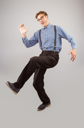 Geeky hipster walking and looking at camera on grey backgroundの写真素材