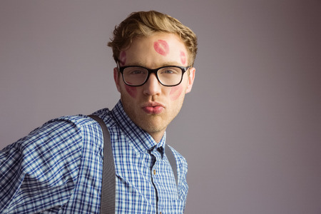 Geeky hipster covered in kisses on grey backgroundの写真素材