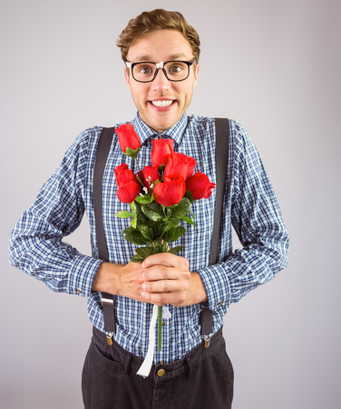 Geeky hipster holding a bunch of roses on grey backgroundの写真素材
