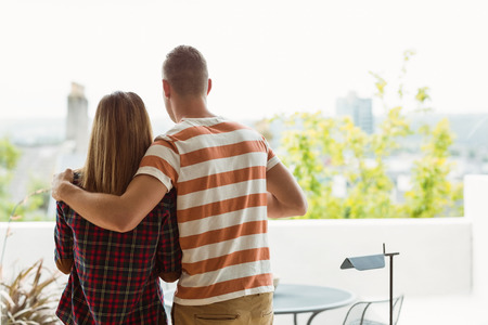 Cute couple looking out the window at home in the kitchenの写真素材