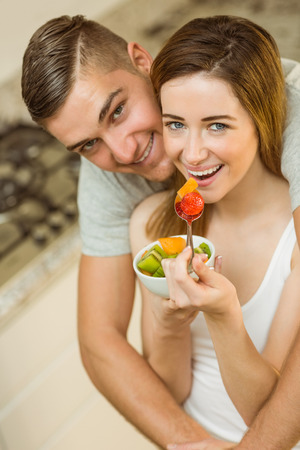 Couple eating fruit salad at breakfast at home in the kitchenの写真素材