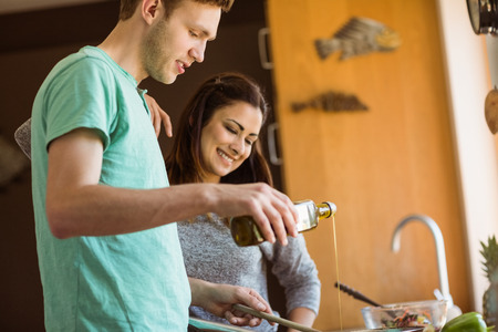 Cute couple preparing food together at home in the kitchenの写真素材