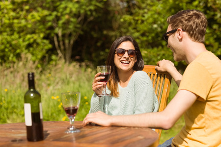 Young couple enjoying red wine outside in the gardenの写真素材