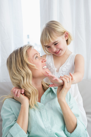 Portrait of a mother and daughter behind her on the couch at home in the living roomの写真素材