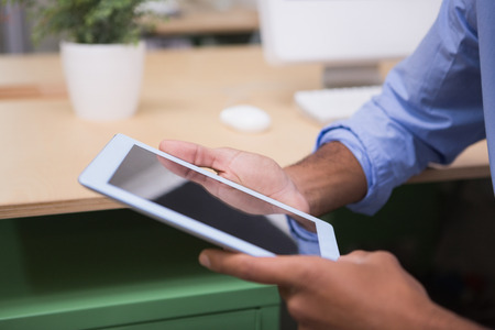 Close up of cropped businessman using digital tablet at office desk