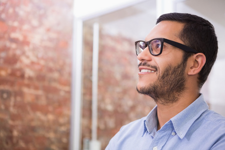 Close up of thoughtful young businessman looking away in officeの写真素材