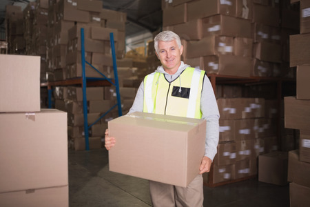 Portrait of worker carrying box in the warehouseの写真素材