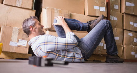 Side view of male worker lying on the floor in warehouseの写真素材