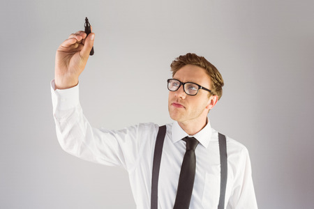 Geeky businessman writing with marker on grey backgroundの写真素材