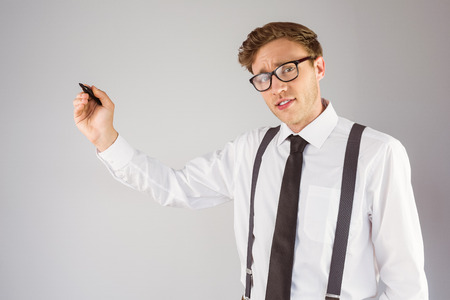 Geeky businessman writing with marker on grey backgroundの写真素材