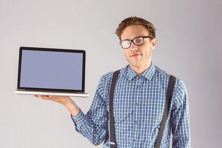 Geeky businessman showing his laptop on grey backgroundの写真素材