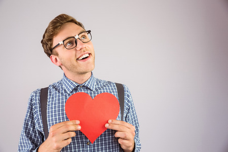 Geeky hipster holding a heart card on grey background